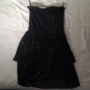 Svart paljettklänning - Snygg svart tubetop klänning med paljetter och utan axelband från Gina young i storlek 146-152. Perfekt för en glittrig kväll. Klänningen har en volangdetalj och perfekt för fester eller nyår🎉😙 någon lös tråd(skriv för bättre bild) pris kan diskuteras❗️❤️❤️😙