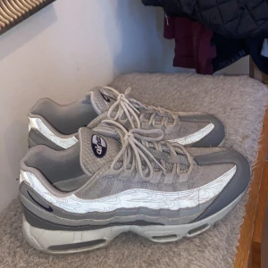 Air max 95 skor - Säljer ett par grå Nike Air Max sneakers med snörning och en stilren design. Skorna har en synlig Air Max-dämpning i sulan och är perfekta för en sportig look.