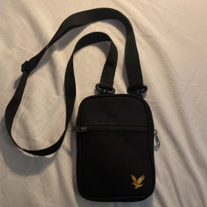 Svart axelväska från lylescott med gul logotyp ny pris runt 350 cm,nästan helt oandvänd! - Snygg och praktisk svart axelväska med justerbar rem och dragkedja. Väskan har ett stilrent fågelmotiv i gul på framsidan. Perfekt för att bära med sig det nödvändigaste!