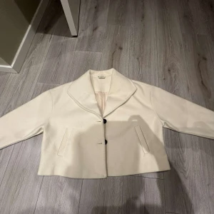 Kappa från Noisy May - Säljer en stilren kappa från Noisy May. Den har en klassisk krage och knäpps med knappar framtill. Perfekt för en chic look. Passar till många olika outfits!