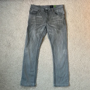 Grå jeansbyxor - Snygga grå jeansbyxor med klassisk femficksdesign och knappgylf. De har en rak passform och är perfekta för en avslappnad stil. Byxorna har en diskret tvättad look som ger dem en modern touch. Sitter som W31 L32~