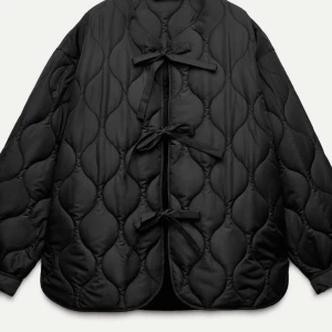 Svart quiltad jacka med rosetter - Snygg svart quiltad jacka med unika rosettdetaljer framtill. Jackan har en oversized passform och långa ärmar, perfekt för höst och vår. Den quiltade designen ger en extra touch av stil. Jackan är i st S. Säljer denna jacka pga råkade beställa 2 st. (Ordinarie pris 400kr) Jag säljer för 350kr vid snabb affär 300kr!!!!