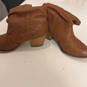 Bruna boots med klack - Snygga bruna boots i skinnimitation med en stabil klack. De har en avslappnad passform och en stilren design som passar perfekt för höst och vår. Perfekta för att ge din outfit en trendig touch.använd ett par gånger