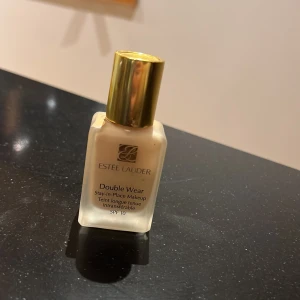 Estée Lauder Double Wear Foundation - Säljer en Estée Lauder Double Wear Stay-in-Place Makeup i nyansen 1N1 Ivory Nude. Denna foundation har SPF 10 och ger en långvarig, hållbar finish. Perfekt för en jämn och naturlig look. Halva burken kvar