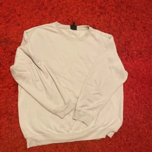 Vit sweatshirt från H&M - Säljer en vit sweatshirt från H&M i relaxed fit. Tröjan har långa ärmar och en rund halsringning, perfekt för en avslappnad stil. Passar bra till både jeans och mjukisbyxor.