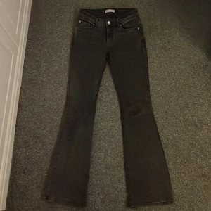 Gråa bootcut jeans - Snygga gråa bootcut jeans med låg midja och klassisk femficksdesign. De har en knapp och dragkedja framtill. Lite slitningar längst ner men inget man tänker på när dom används.