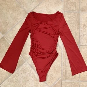 Röd långärmad onepiece bodysuit - Långärmad röd onepiece med utsvängda armar. Toppen är aldrig använd och är därför i gott skick. Den är i stl xs. Klicka gärna på köp nu och meddela för eventuella frågor. :)