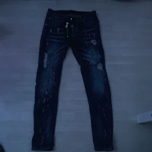 DSQUARED Mörkblå jeans ÖPEN FÖR BUD!!! - Snygga mörkblå DSQUARED jeans med slitningar och coola detaljer. De har en unik dragkedja framtill och stänk av färg som ger en edgy look. Perfekta för en avslappnad stil med en twist.