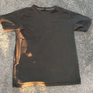 Svart Sail Racing t-shirt - Svart T-shirt som är köpt från Kids Brand Store. Det är solen som syns på bilden. T-shirten är i bra skick, den är använd ett par gånger. Den är i storlek 176 (junior storlek) S för vuxna. 