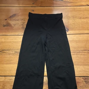 Svarta byxor från Nelly - Snygga svarta byxor från Nelly i en klassisk design. De har en hög midja och en rak passform som ger en stilren look. Perfekta för en chic och enkel stil.