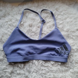 Lila sporttopp från Adidas - Säljer en lila sporttopp från Adidas med logga på framsidan. Banden är ei justerbara. Använts få antal gånger. Lappen är bort klippt för att den kliade. Passar mig som normalt har xs/s.