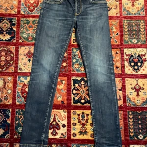 Blå tramarossa jeans - Snygga blå jeans med raka ben och klassisk design. Byxorna har en midwaist passform och är tillverkade i slitstarkt denim. Perfekta för en avslappnad stil. De finns en fläk på insidan som jag inte vet vad de är för de har inte gåt bort i tvättmaskinen. Om du har några frågor fråga på mvh Theodor 