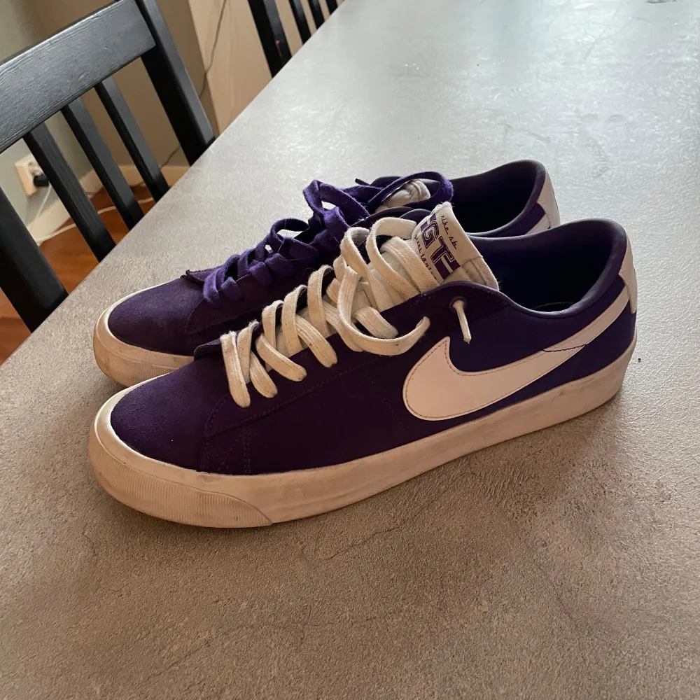 Säljer ett par lila Nike sneakers med vit sula och vit swoosh. Skorna har snörning och en stilren design, perfekt för vardagsbruk.. Kengät.