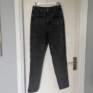 Svarta högmidjade jeans - Snygga svarta högmidjade jeans med en klassisk straight fit. Perfekta för en stilren look, oavsett tillfälle. De har en knapp- och dragkedjestängning framtill.