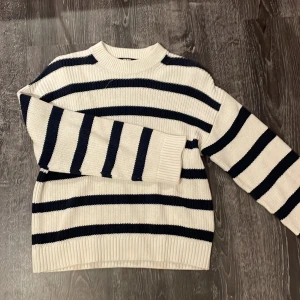 Randig stickad tröja från BikBok - Säljer en snygg randig stickad tröja från BikBok i storlek XS. Tröjan har ett klassiskt mönster med vita och mörkblå ränder och långa ärmar. Perfekt för en stilren look!
