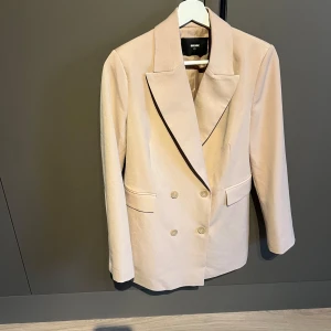 Beige kavaj  - Beige kavaj från Bikbok strl XS helt oanvänd, i nyskick utan prislapp. Nypris 699kr