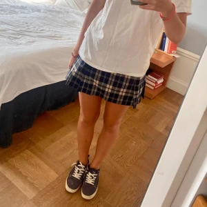 Rutig kjol - Snygg rutig kortkjol i blått, vitt och svart. Kjolen har en klassisk plisserad design som ger en stilren look. Perfekt för en avslappnad och trendig stil.