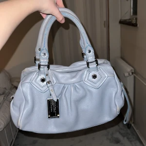 Marc Jacobs väska  - Så fin ljusblå/grå Marc Jacobs väska som är i väldigt bra skick men lite användning på undersidan. Det märks inte. Intressekoll för bästa bud. 