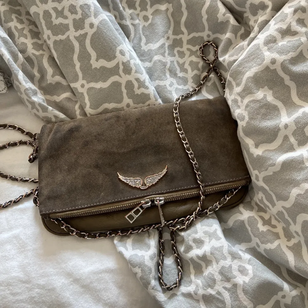 Snygg brun axelväska från Zadig i mocka med en elegant kedja och ett dekorativt emblem framtill. Väskan har en dragkedja och är perfekt för att ge en stilren touch till din outfit.. Laukut & Käsilaukut.