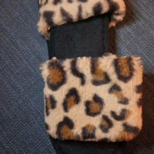 Leopardmönstrade tofflor med päls - Säljer ett par mysiga tofflor med leopardmönster och mjuk päls. Perfekta för att hålla fötterna varma och stiliga hemma.