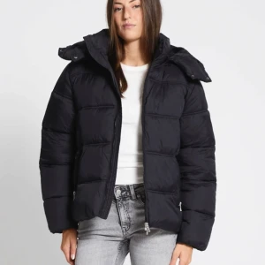 Svart pufferjacka med huva från lager 157 - Snygg svart pufferjacka med huva och dragkedja. Perfekt för kyliga dagar med sin vadderade design. Jackan har långa ärmar och en bekväm passform.