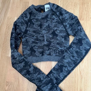 Träningstopp från Gymshark - Snygg grå tröja/topp från Gymshark Camo. Endast använd ett fåtal gånger så i väldigt bra skick & utan anmärkningar!