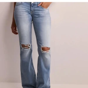 Ljusa bootcut jeans med slitningar - Snygga ljusblå bootcut jeans med slitningar på knäna. Perfekta för en avslappnad stil. De har en klassisk femficksdesign och en bekväm passform. 
