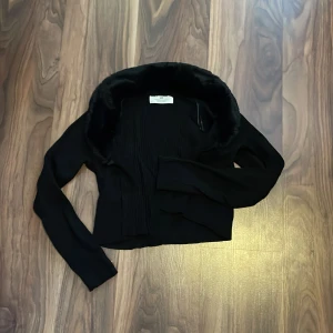 Svart kofta  - Säljer en svart kofta från h&m i storlek 146/152. Den har fuskpäls krage och en knapp vilket man kan se på bilden. Tröjan är använd ett antal gånger men är i bra skick och har inga defekter. 