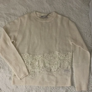 Vit tröja med spetsdetalj från Zara - Säljer en trendig och stilren vit tröja från Zara med vacker spetsdetalj över magen. Tröjan har långa ärmar och en mjuk, bekväm passform. Perfekt för en elegant och avslappnad look. (Storlek M men passar S) 🤍🤍