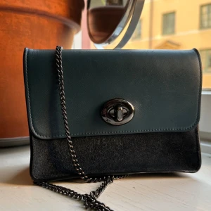 Coach handväska - Mindre handväska från coach i mörkgrönt/lite blåa nyanser. Mycket gott skick, inga slitningar/märken. Nypris 2000kr, inköpt för 6-7 år sedan. Köparen står för frakt och inga returer 