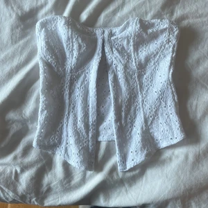 Vit spetskorsett - Säljer en superfin vit korsett med spetsdetaljer. Den har en snygg knäppning framtill och är perfekt för en somrig look. Passar både till fest och vardag!