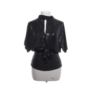 Svart glittrig topp med knyt - Snygg svart glittrig topp med korta ärmar och en knytning framtill. Perfekt för festliga tillfällen! Toppen har en liten öppning vid halsen. Från Sisters Point i storlek XS!❤️