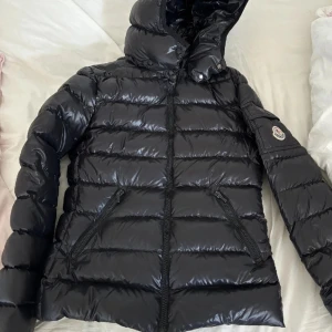 Moncler bady down jacket - Såå snygg moncler dun jacka, nypris är 9300kr, använd 1 vinter. Väldigt bra skick! Några få tecken på användning som att den tappat lite färg på dragkedja storlek 14y men passar mig som vanligtvis bär S💕 Serietidiningen inuti sitter lite löst