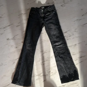 Svarta jeans från Gina Tricot - Säljer ett par svarta jeans från Gina Tricot i storlek 158. De har en klassisk femficksdesign med knappar och dragkedja fram. Jeansen har en bootcut-stil som ger en snygg siluett. Perfekta för både vardag och fest!