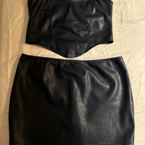 Mörkblå Faux Leather set Motel Rocks - Topp använd 1 gång, kjol använd 2 ggr. Storlek L men passar M. Ord pris för båda ca 500kr. Hör av dig om du enbart är intresserad av ett av plaggen så går det att diskutera!