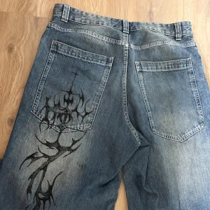 Baggy jeans med tryck - Blåa jeans med snygg tvätt och mönster på bakfickan  Det är byxor från bershka som jag har målat på