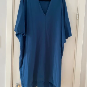 Marinblå v-ringad klänning från COS i strl M - Marinblå v-ringad klänning från COS i strl M.  Använd men i fint begagnat skick.  Mått Över bröstet: ca 87 cm Längd från axeln och ner: ca 93 cm  100% bomull   Kommer från ett djur och rökfritt hem.