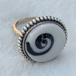Silverring med svartvit spiraldesign - unik silverring med en cool svartvit spiraldesign på toppen. Ringen har en detaljerad kant runt den stora, runda stenen som ger den en vintagekänsla. Perfekt för att ge din outfit en edgy touch! osäkert om materialet Strl 18mm