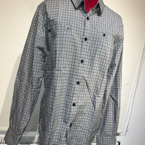 Grå rutig skjorta från Matinique - Snygg grå rutig skjorta från Matinique i storlek M. Skjortan har långa ärmar och knappar framtill samt på bröstfickorna. Perfekt för både vardag och festliga tillfällen. Den är i mycket bra skick och redo att bäras av någon som vill ha en stilren look.