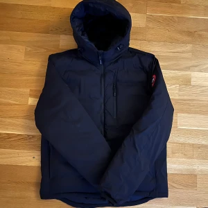 Svart dunjacka från Canada Goose - Säljer en svart dunjacka från Canada Goose i modellen lodge hoody i mycket bra skick 9/10.          Nypris ligger runt 8-9 tusen. Hör av er vid frågor eller intresse så löser vi något bra! Kvitto finns 