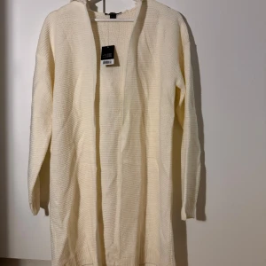 Beige stickad kofta med huva - Säljer en supermysig beige stickad kofta med huva. Perfekt för kyliga dagar och att mysa i hemma. Den har långa ärmar och en öppen design utan knappar. Passar perfekt till höst och vinter. 🧥✨