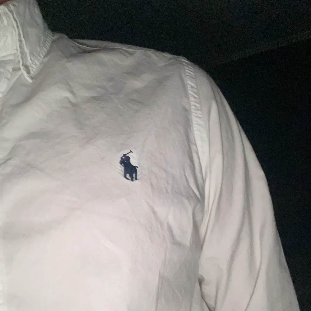 Säljer en klassisk vit skjorta från Polo Ralph Lauren i storlek M. Skjortan är slim fit och har långa ärmar med knappar. Den är i bomull och har den ikoniska broderade loggan på bröstet. Perfekt för både vardag och fest!. Skjortor.