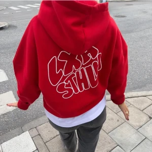 Röd hoodie med tryck - Säljer en oversize cool röd hoodie med stort vitt tryck på ryggen från Lxa som är slutsåld. Den är sparsamt använd! Hör av er vid fler bilder💕