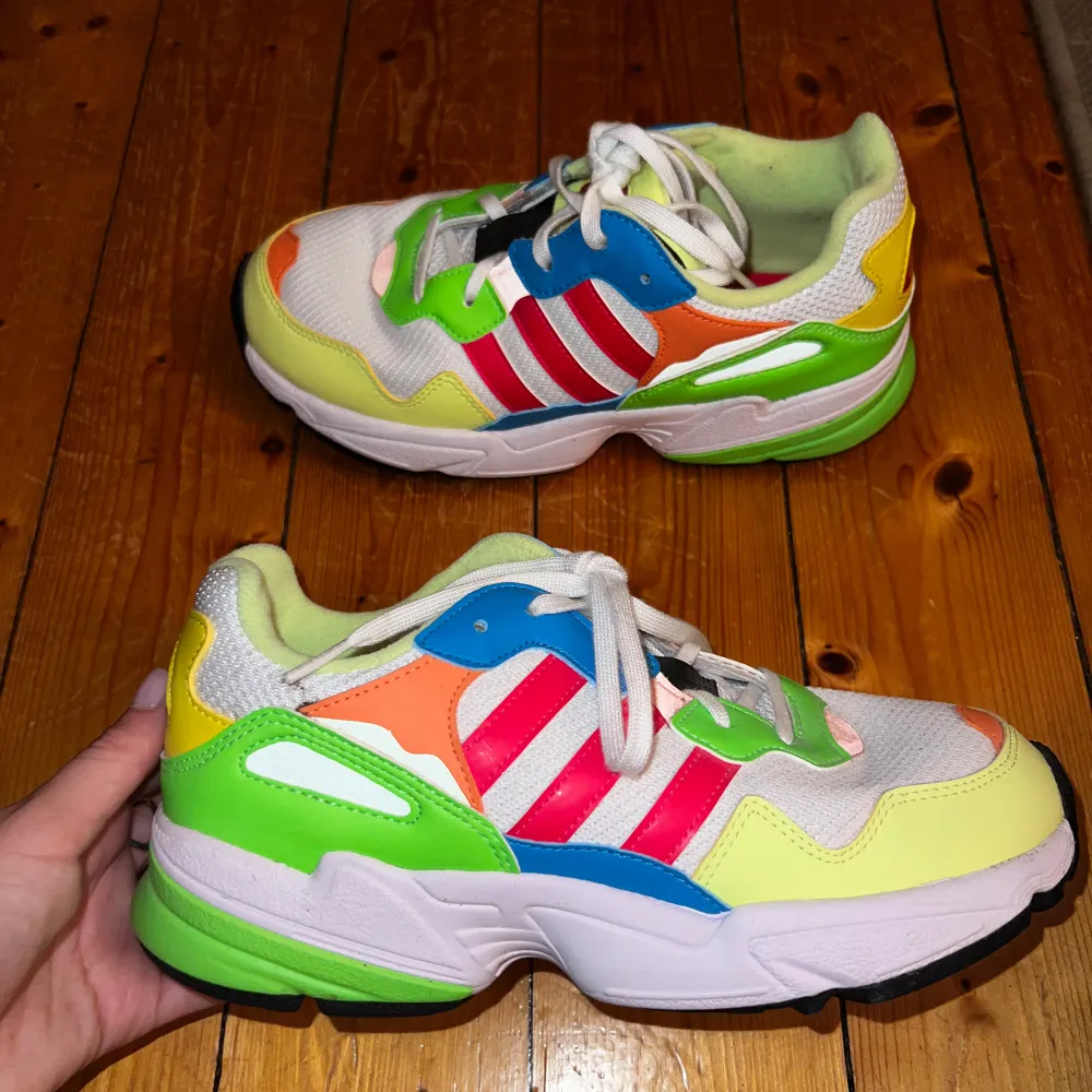 Säljer ett par supercoola och färgglada Adidas sneakers i storlek us 6,5 (eu 38,5). Skorna har en mix av grönt, blått, orange och rosa/rött med vita snören. Perfekta för att liva upp vilken outfit som helst! De är i bra skick, men har fått någon smutsfläck under de få gånger de använts. Köparen står för frakt. . Skor.