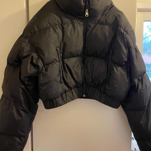 Svart croppad pufferjacka från Shein - Säljer en svart croppad pufferjacka från Shein i storlek XS. Jackan har en dragkedja framtill och är perfekt för höst och vinter. Den är i mycket bra skick och har en cool, modern stil. Perfekt för att hålla sig varm och snygg! Passar även S 