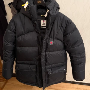Svart dunjacka från Fjällräven - Säljer en svart dunjacka från Fjällräven i nytt skick jackan är i storlek L nypris på den ligger på 10 tusen. Vid mer bilder hör av er priset ej hugget i sten. Dustbag och etiket ingår.