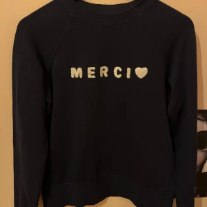 Mörkblå tröja med text - Säljer en superfin mörkblå tröja med texten 'MERCI' och ett hjärta på framsidan. 