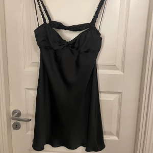 Svart satin klänning - Snygg svart klänning i satin storlek L men den är som en M!! Perfekt för festliga tillfällen med sin eleganta och stilrena look. Klänningen har en snygg design både fram och bak . Ny pris 350kr, med taggar kvar! 💞