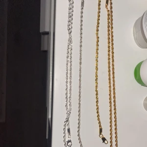 Två kedjehalsband i silver och guld och armband ,SET - Säljer två snygga kedjehalsband och armband , ett i silver och ett i guld. Båda har en vriden design som ger en cool och modern look. Perfekta för att piffa upp vilken outfit som helst, oavsett om det är till vardags eller fest. Passar både killar och tjejer!