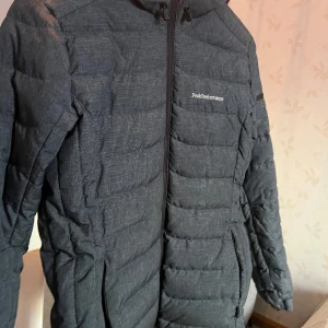 Mörkblå dunjacka från Peak Performance - Säljer en snygg och varm mörkblå dunjacka från Peak Performance. Jackan har en dragkedja framtill och är perfekt för kyliga dagar. Den är i mycket bra skick och passar både till vardags och utomhusaktiviteter. Helt ny och nästan o använd!